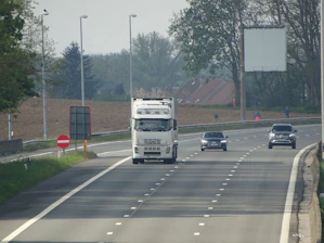 A dynamic highway scene showing multiple trucks crossing a US-Canada border checkpoint with clear signage.