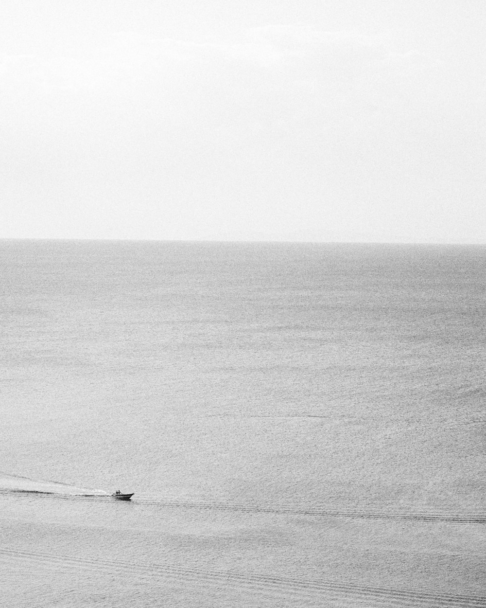 Foto en escala de grises de una persona en barco en el mar