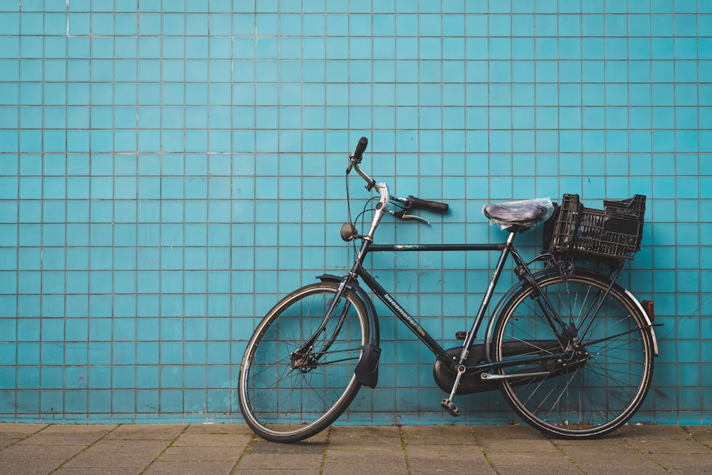 Bicicleta urbana negra estacionada junto a la pared azul