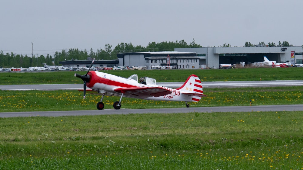 red and white airplane on green grass field during daytime