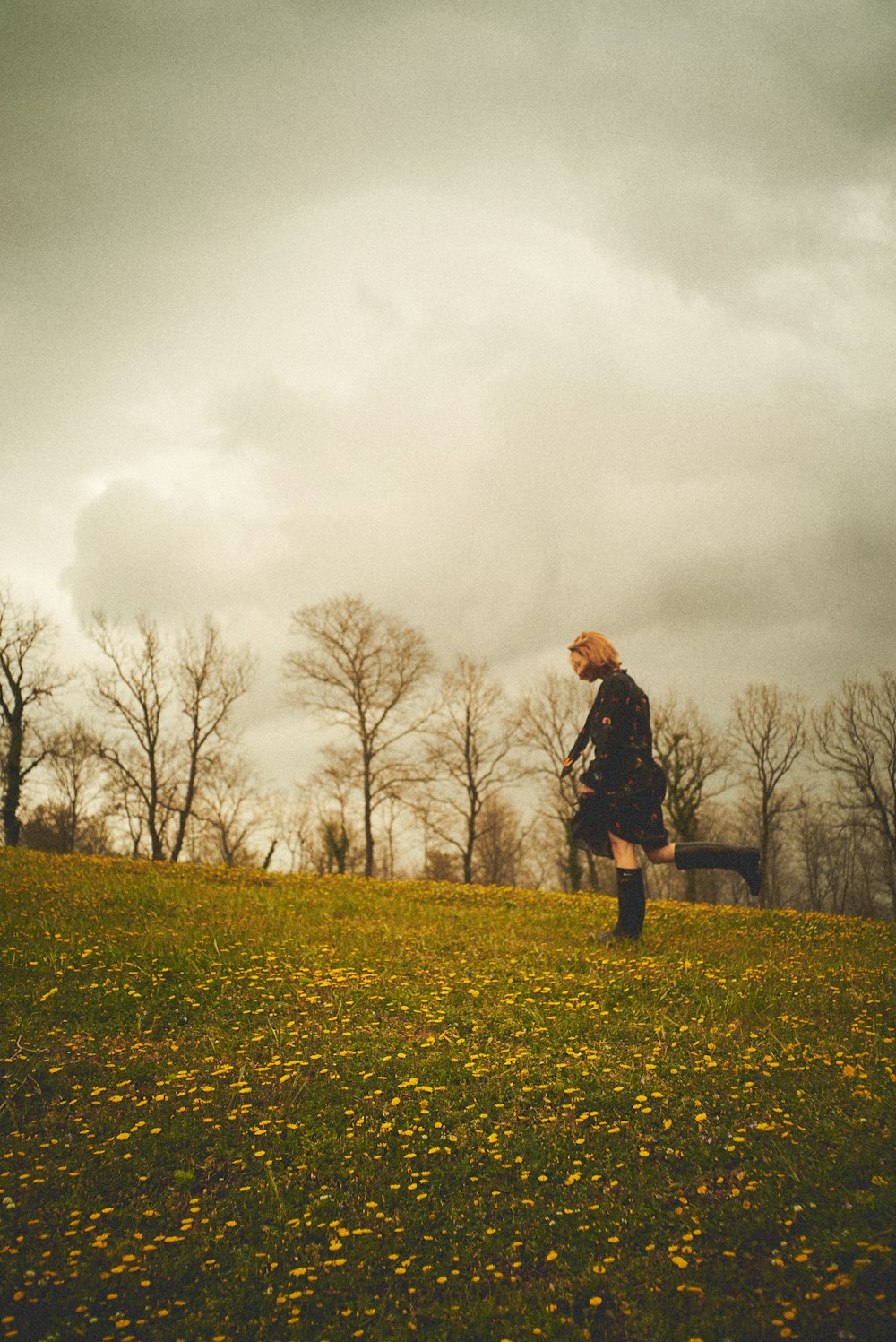 man in black jacket standing on green grass field under gray cloudy sky