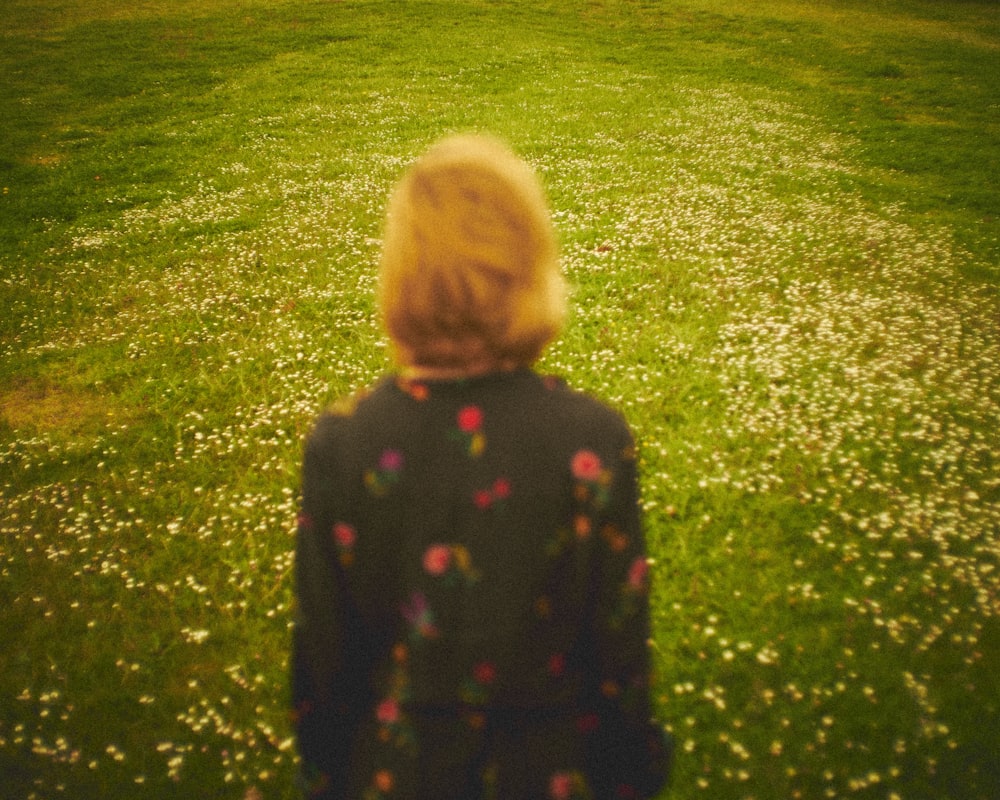 girl in black and green polka dot long sleeve shirt standing on green grass field during