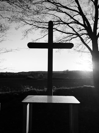 A serene landscape with a cross silhouetted against the sunset.