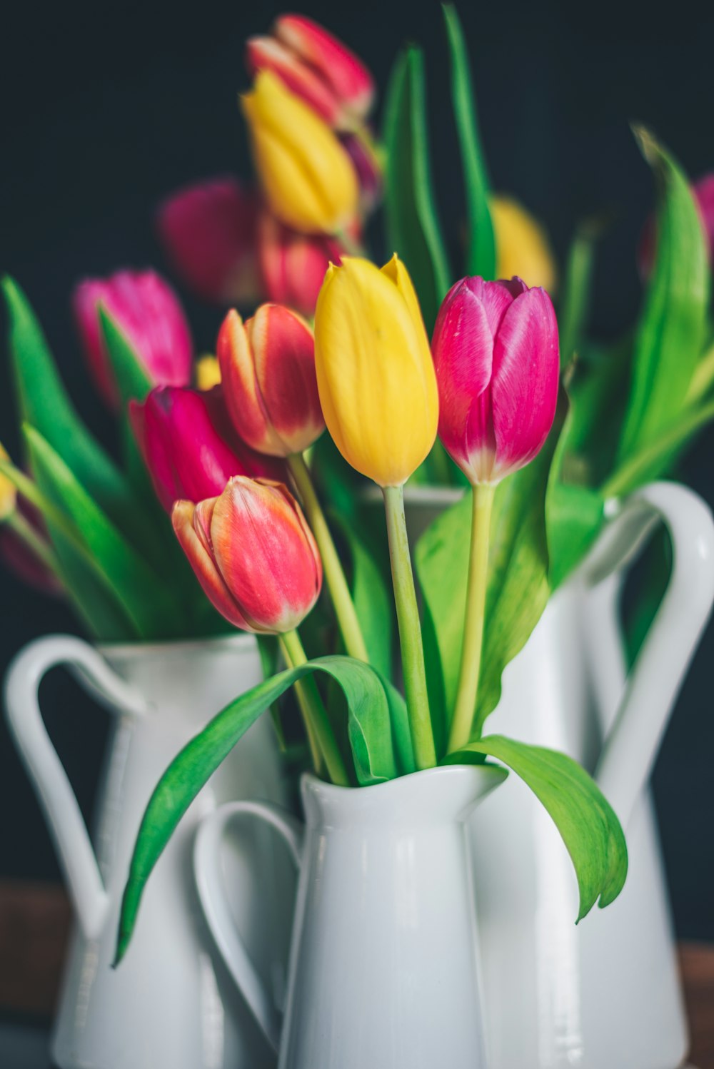 pink and yellow tulips in white ceramic pitcher