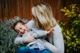 woman in gray sweater carrying girl in blue denim jacket