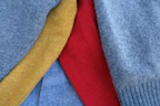 Close-up of colorful, hand-stitched pet clothes laid out on a bright fabric background.