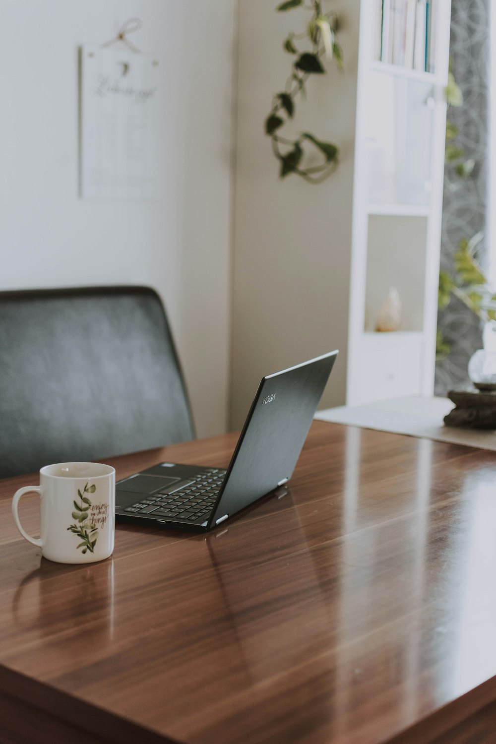 macbook pro beside white ceramic mug on brown wooden table