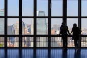 Smiling businesspeople shaking hands in front of a bright city skyline.