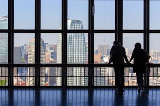 silhouette of man standing in front of glass building during daytime