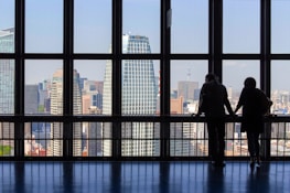 Smiling businesspeople shaking hands in front of a bright city skyline.