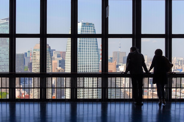 A close-up of hands exchanging house keys with a city skyline in the background.