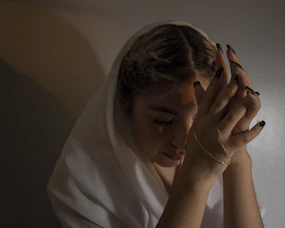 woman in white shirt covering her face with her hands