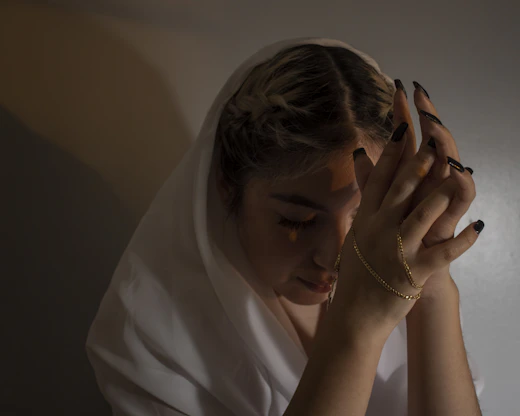 woman in white shirt covering her face with her hands