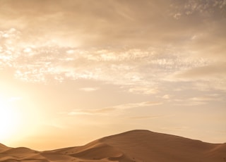 brown sand under white clouds during daytime