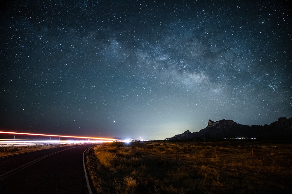 brown grass field near road under starry night