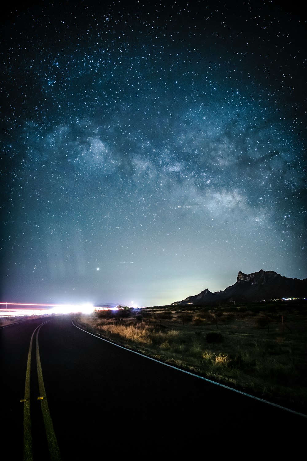 campo di erba verde vicino alla strada sotto la notte stellata