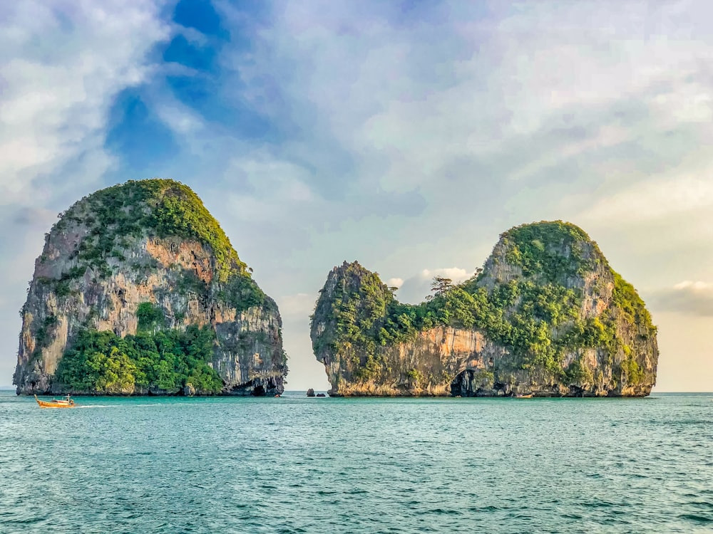 green and brown rock formation on sea under white clouds and blue sky during daytime