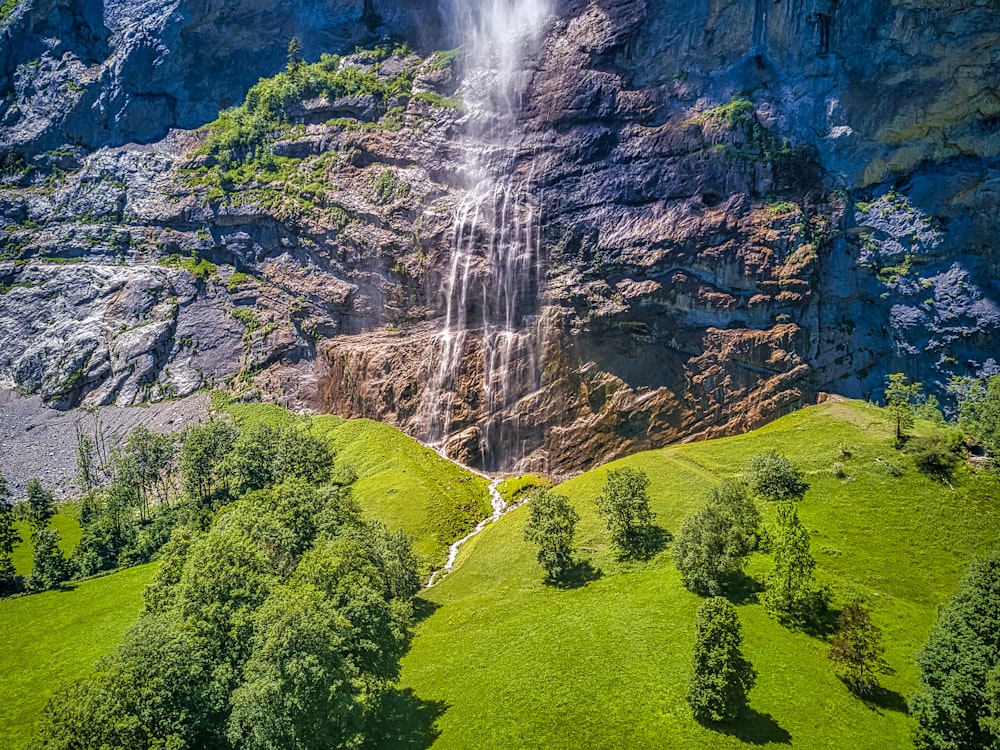 waterfalls on green grass field during daytime