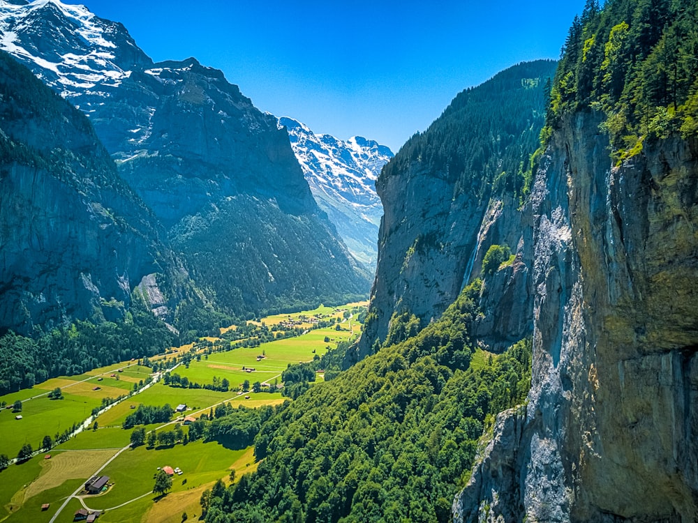 green grass field on rocky mountain under blue sky during daytime