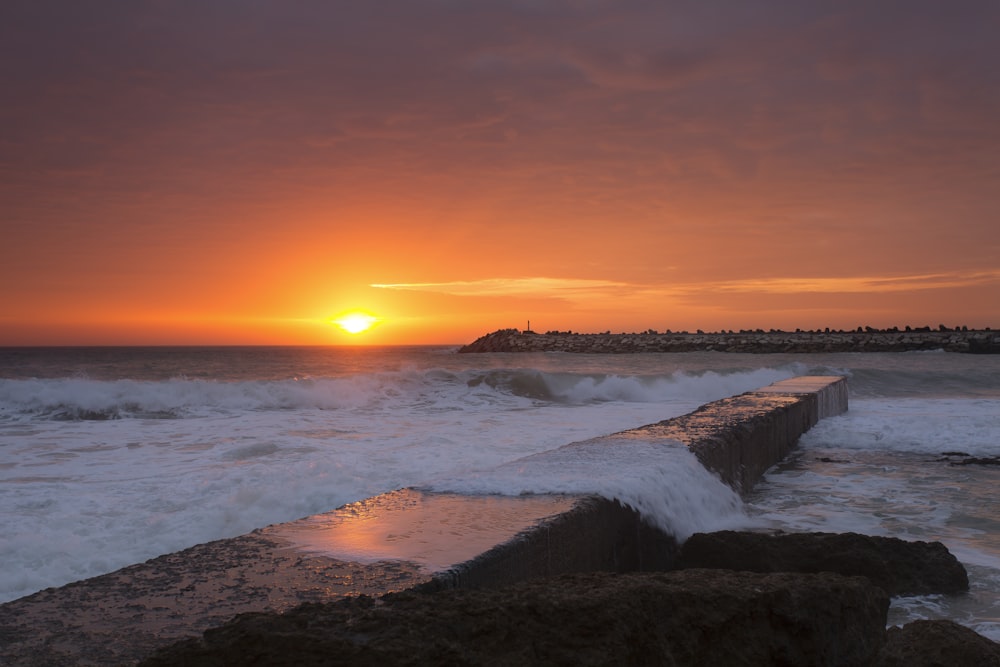 ocean waves crashing on shore during sunset