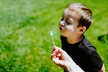A candid moment of a child blowing bubbles during an outdoor wedding ceremony.