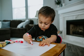 boy in black crew neck shirt writing on white paper