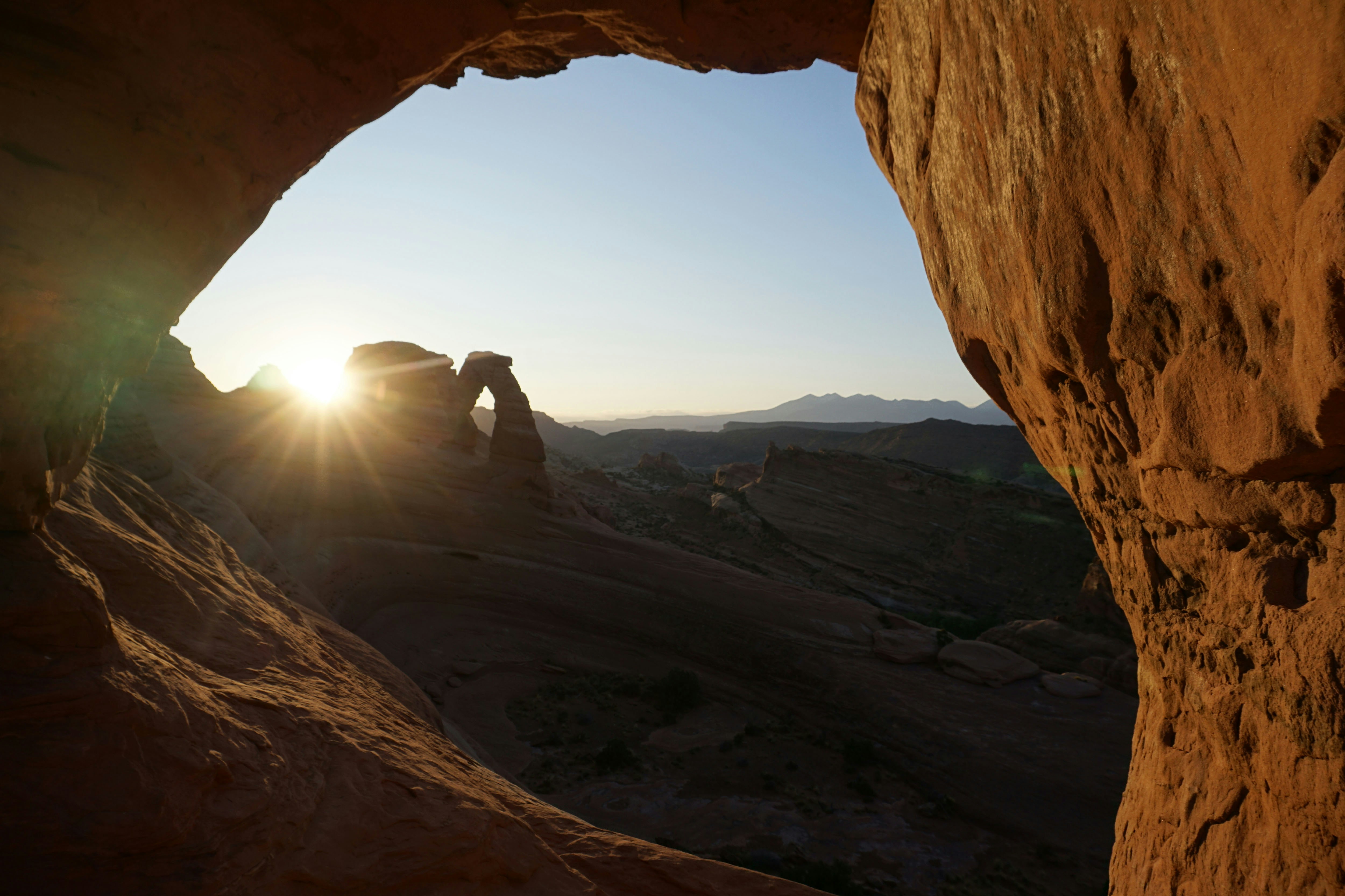 person in black jacket sitting on rock formation during daytime utah teams background
