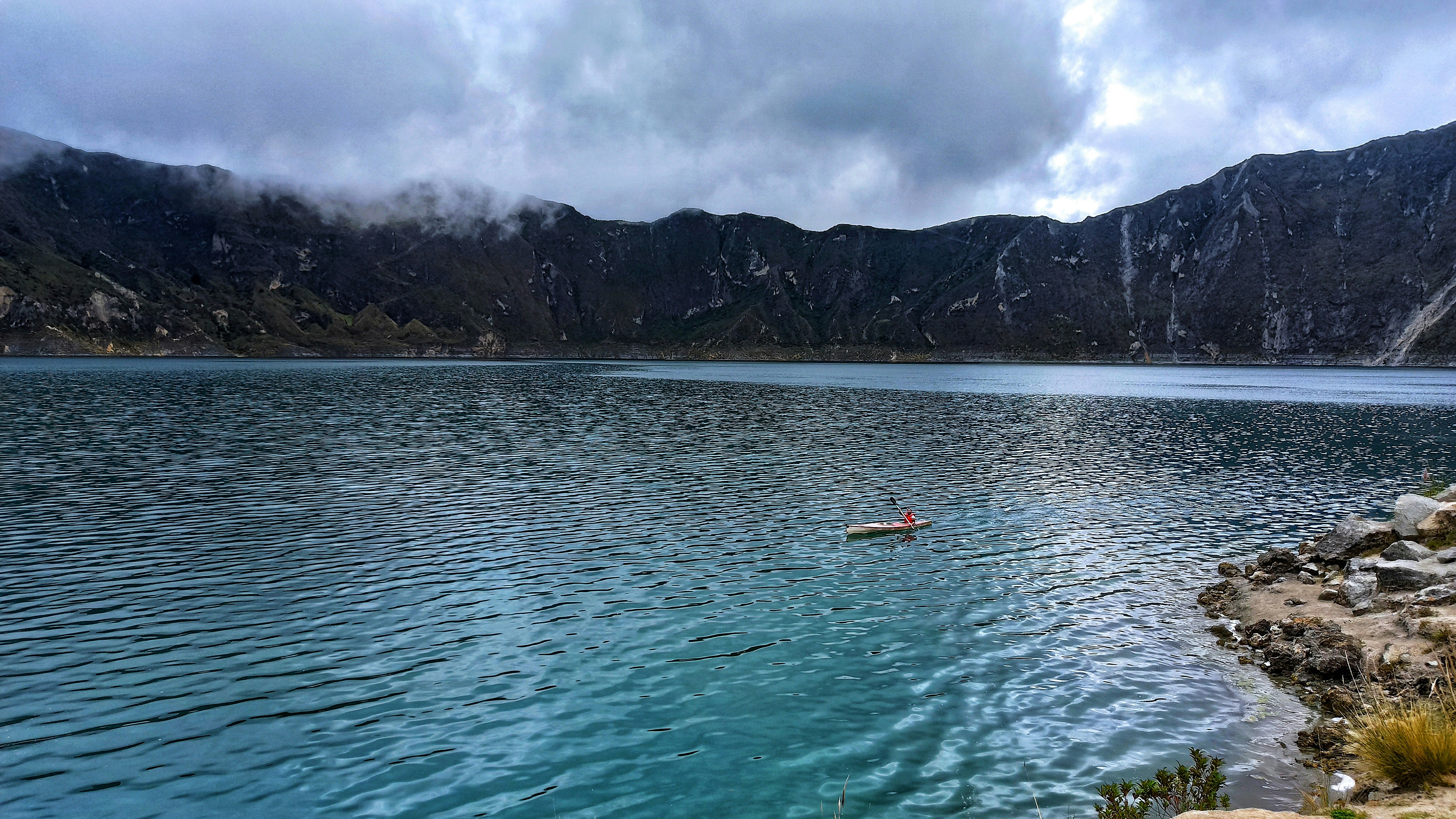 person riding on white and orange boat on sea near mountain during daytime