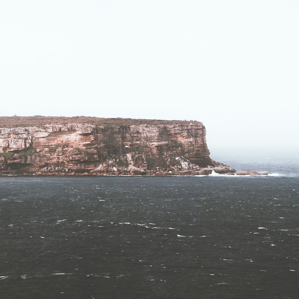 brown rock formation beside sea during daytime