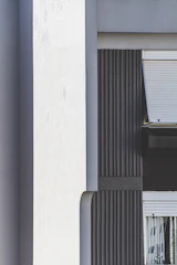 Detailed shot of white EPS wall mouldings with visible coating texture, mounted on a modern building exterior.
