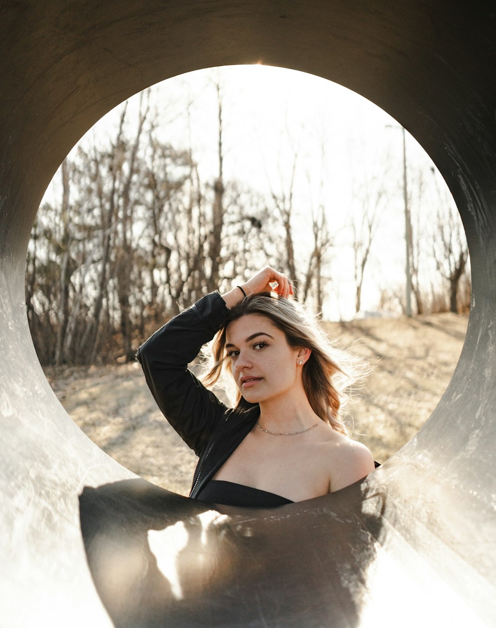 woman in black long sleeve shirt standing in front of brown wooden tunnel