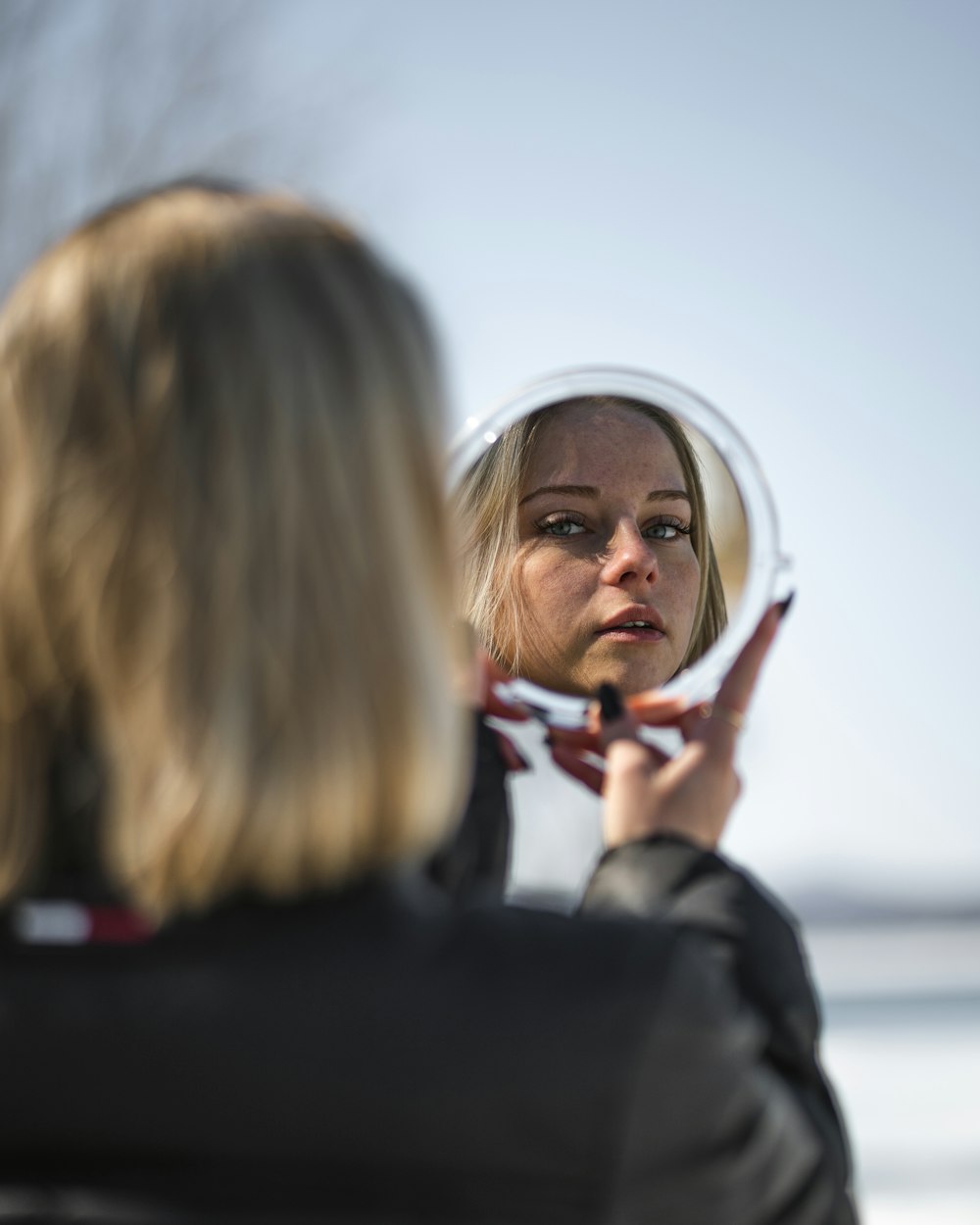 woman in black coat holding magnifying glass