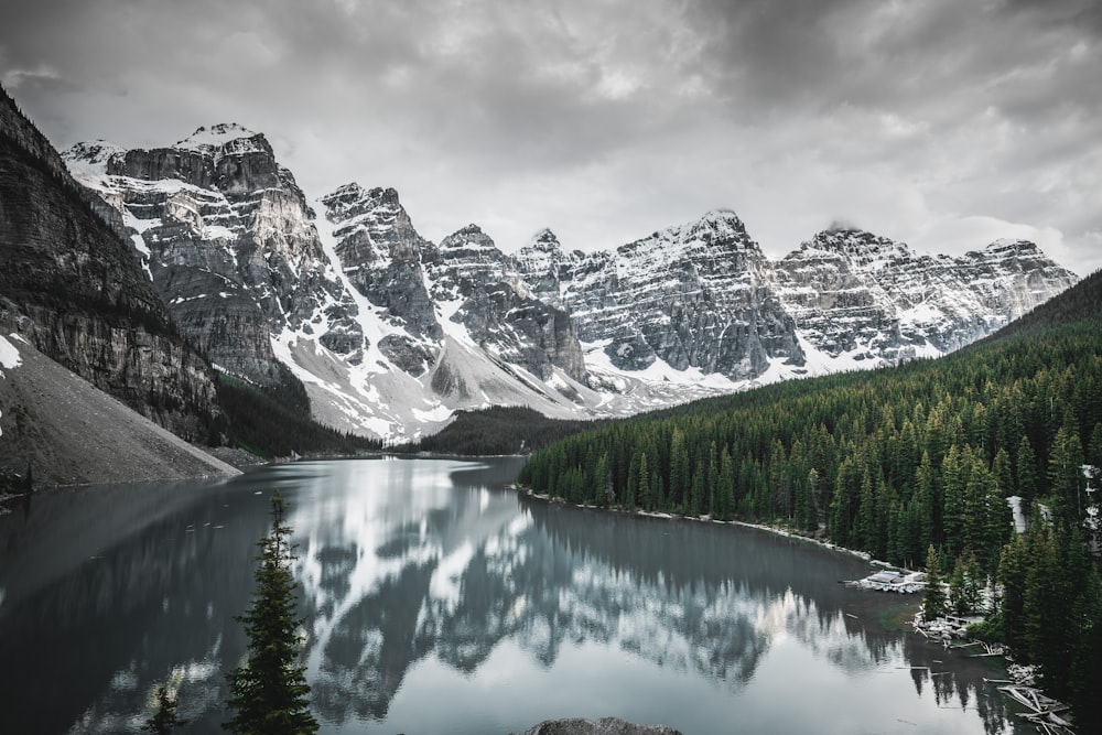 lago perto da montanha coberta de neve sob céu nublado durante o dia