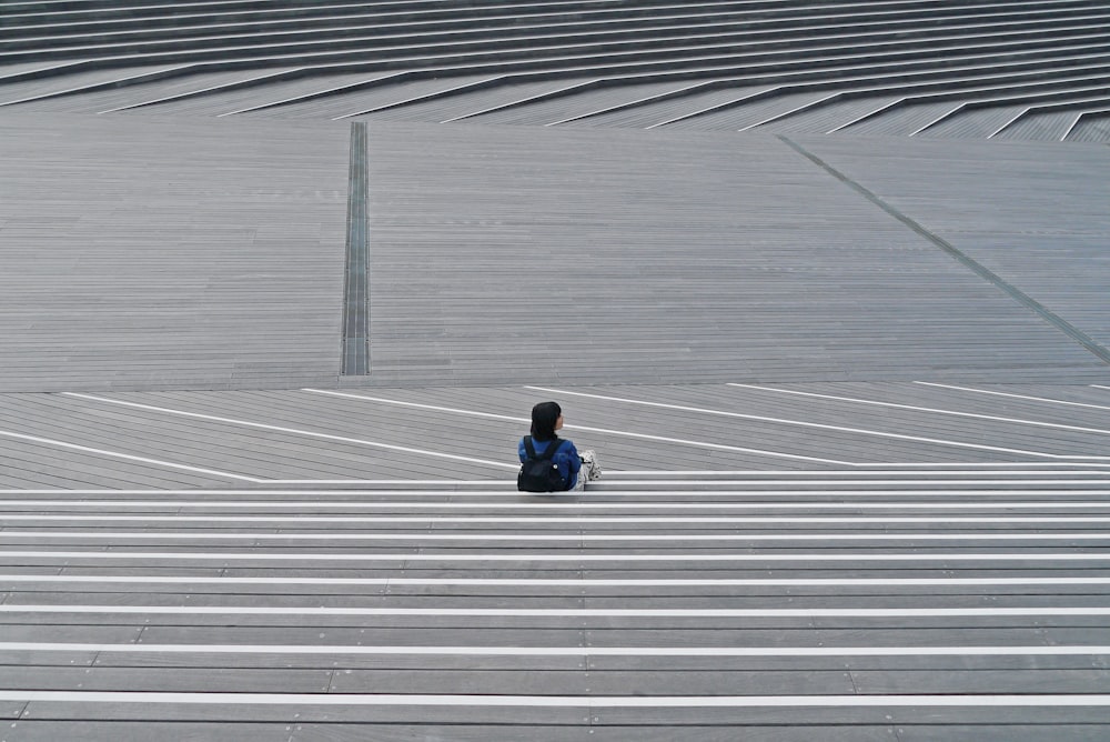 person in black jacket sitting on white and gray concrete floor