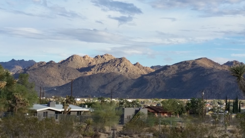 white and brown house near green trees and mountain during daytime