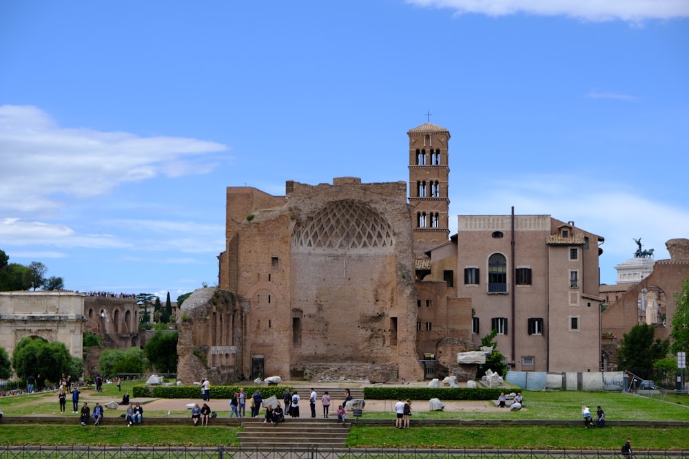 people sitting on green grass field near brown concrete building during daytime