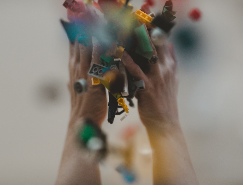 person holding yellow green and blue plastic toys