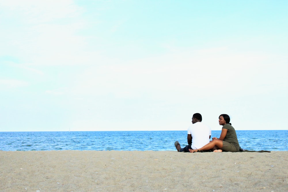couple sitting on beach during daytime