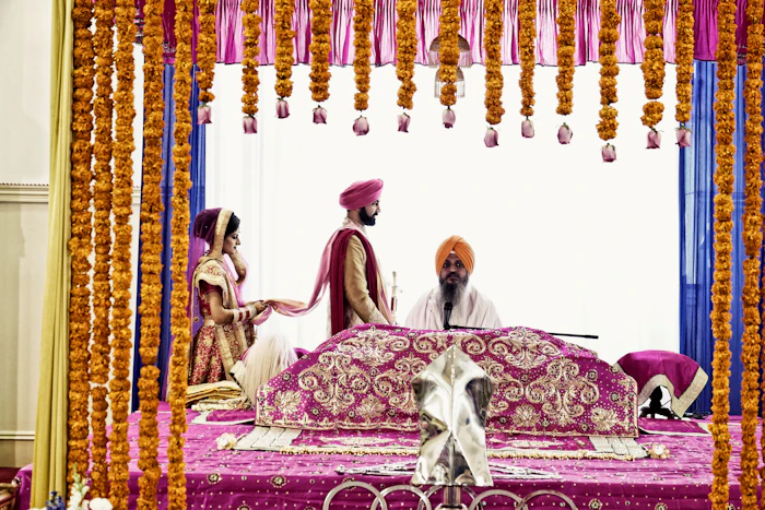 Couple seated on a red and gold floral sofa at a decorated wedding reception