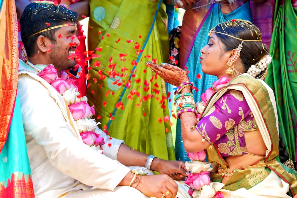 woman in green and pink sari dress holding baby in white dress