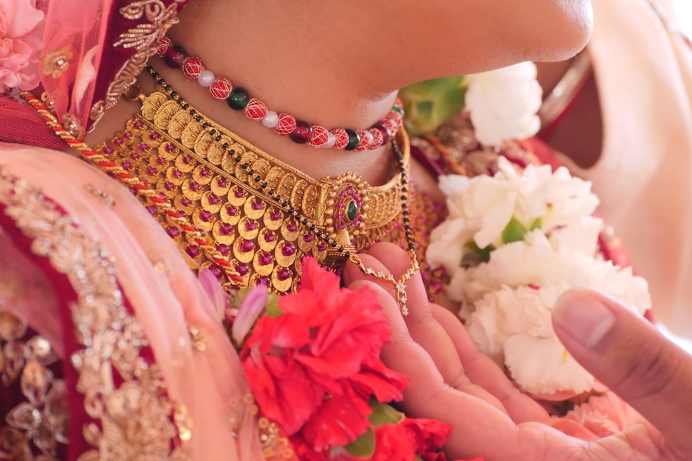 Frau mit goldenem und rosa Perlenarmband