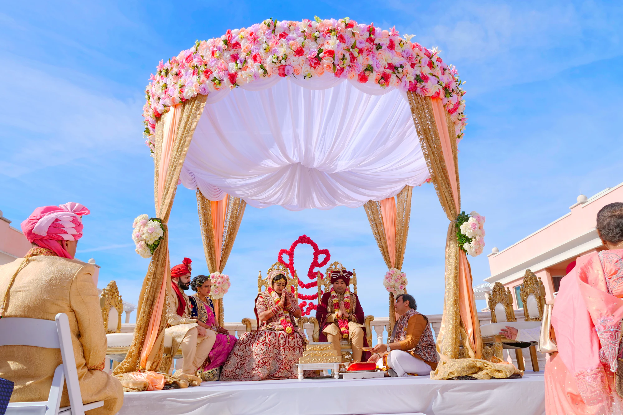 Indian bride and groom seated beneath a floral canopy during the wedding ceremony
