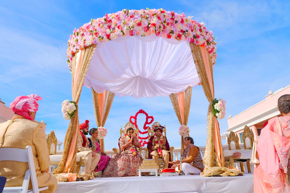 An outdoor Indian wedding ceremony under a floral mandap