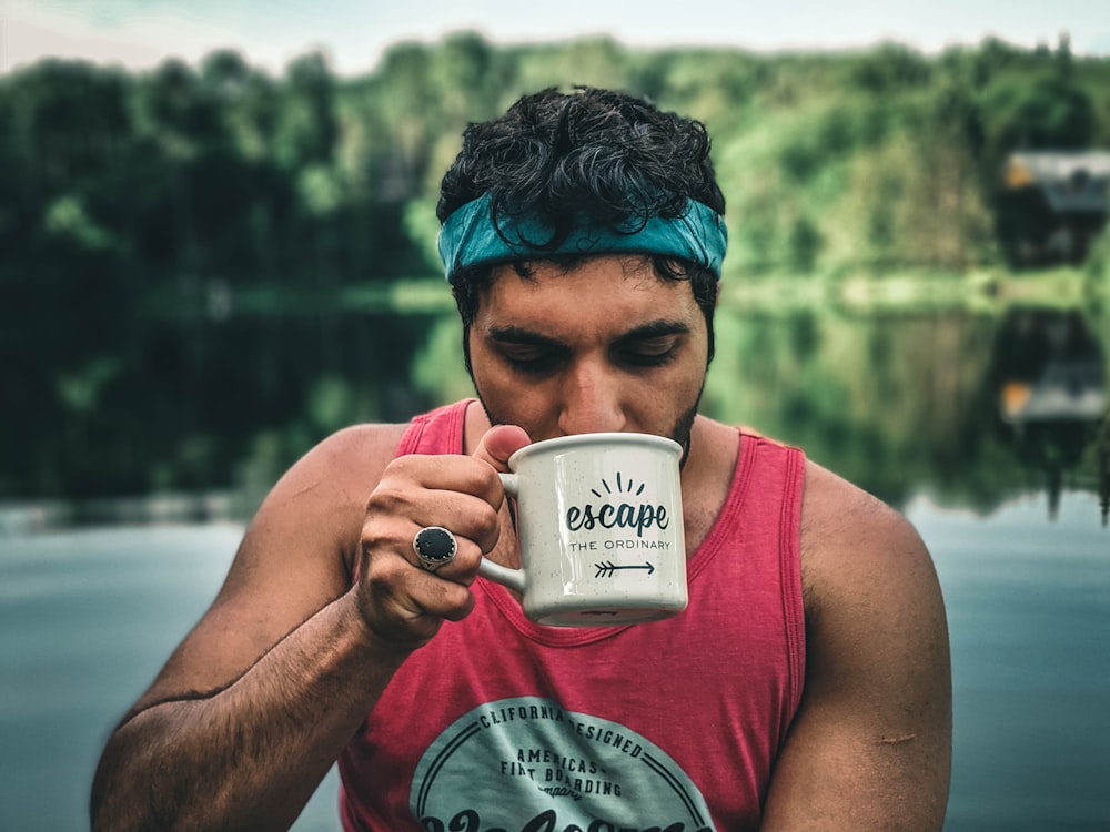 woman in pink tank top holding white ceramic mug