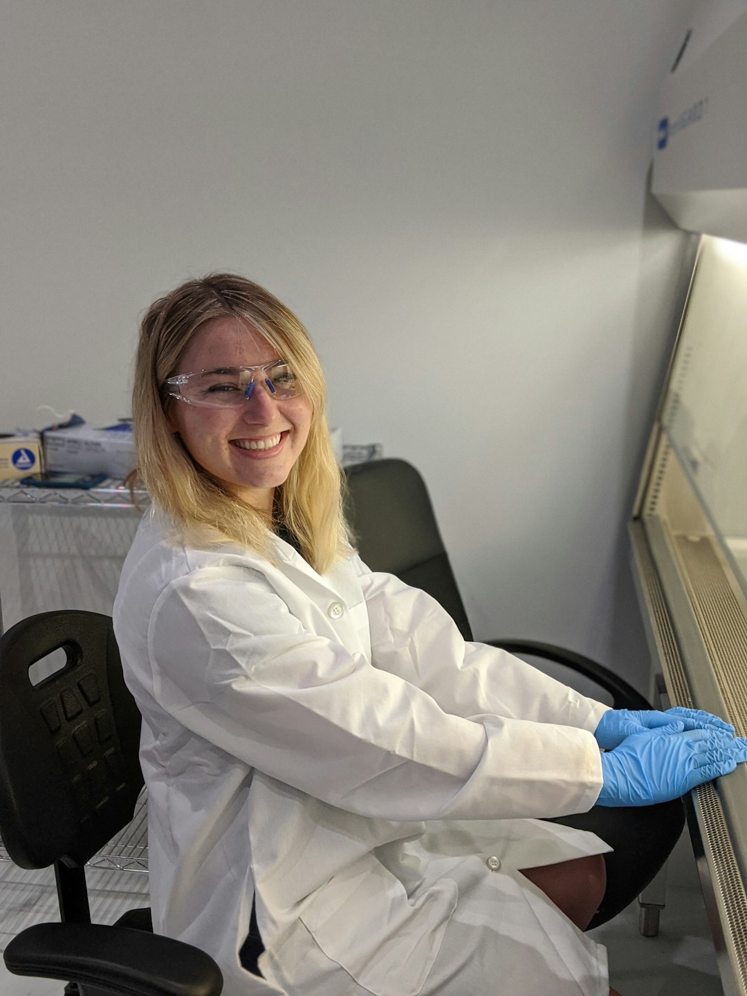 Female scientist using laminar flow hood in sterile laboratory.