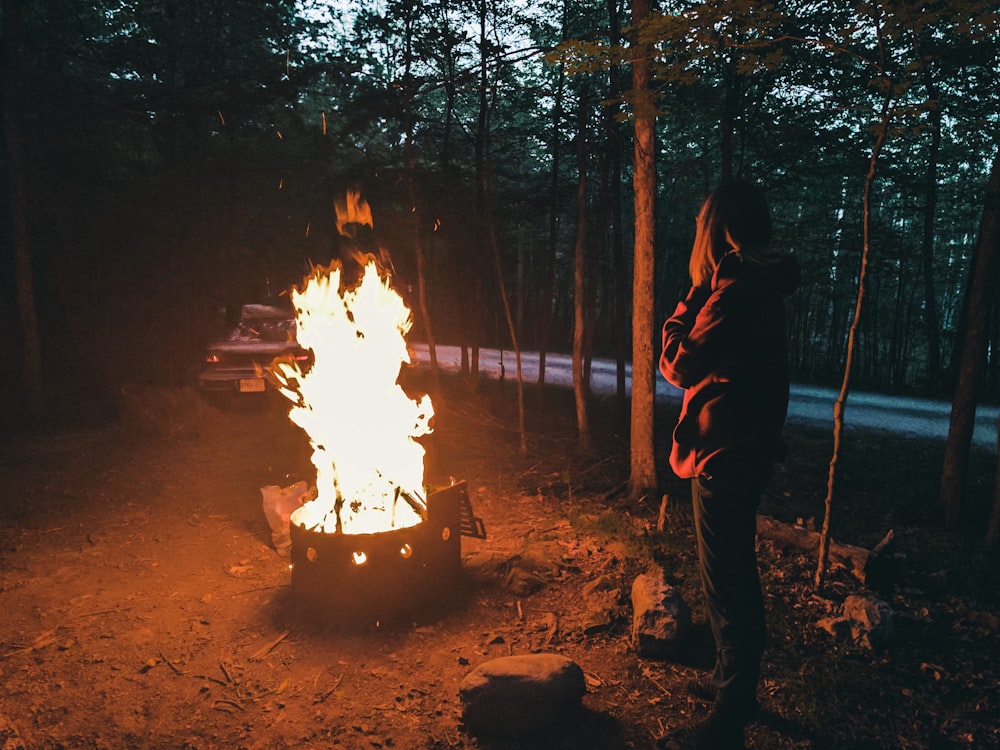 man in black jacket and black pants standing near bonfire during night time