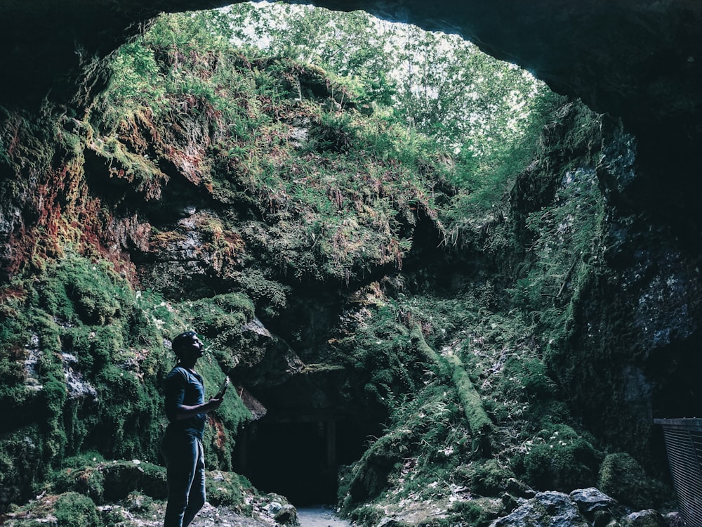 Hombre con chaqueta negra y pantalones negros de pie en el río rocoso durante el día