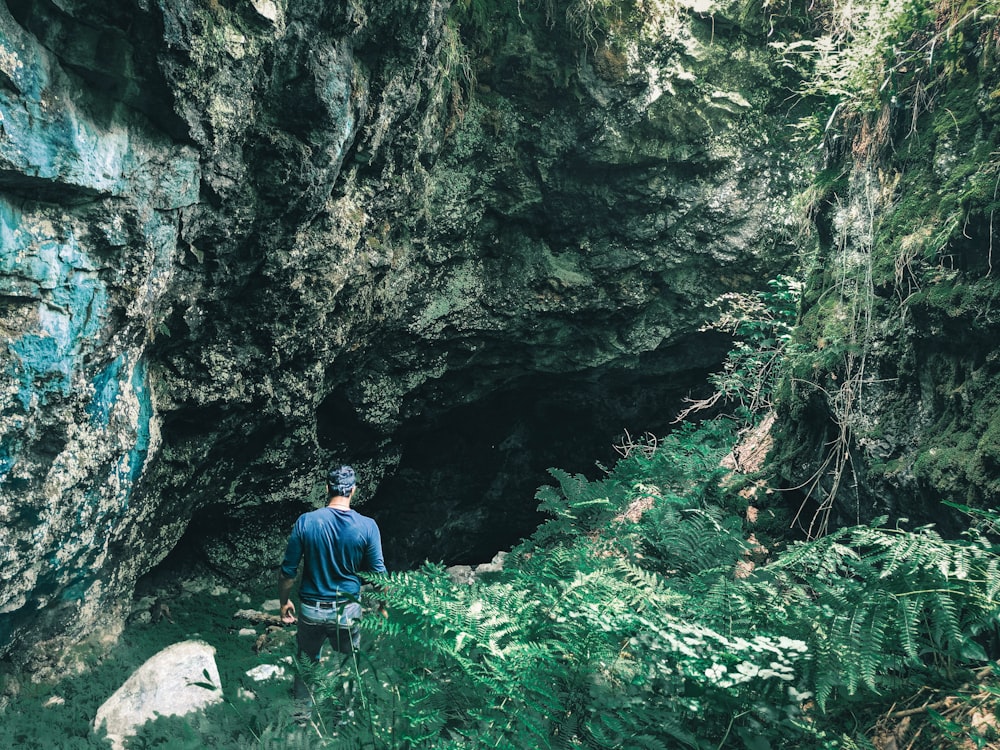 man in blue jacket and blue denim jeans sitting on rock