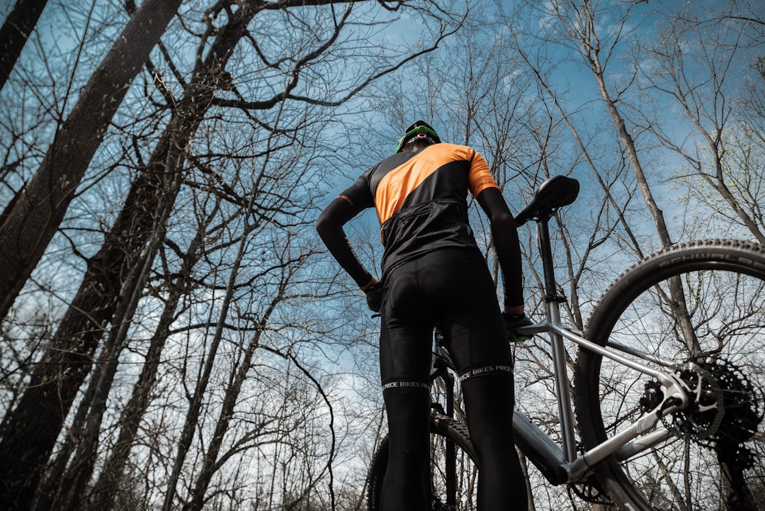 man in orange shirt and black shorts riding bicycle