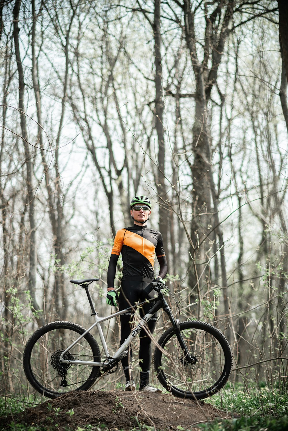 man in orange jacket riding on black mountain bike in forest during daytime
